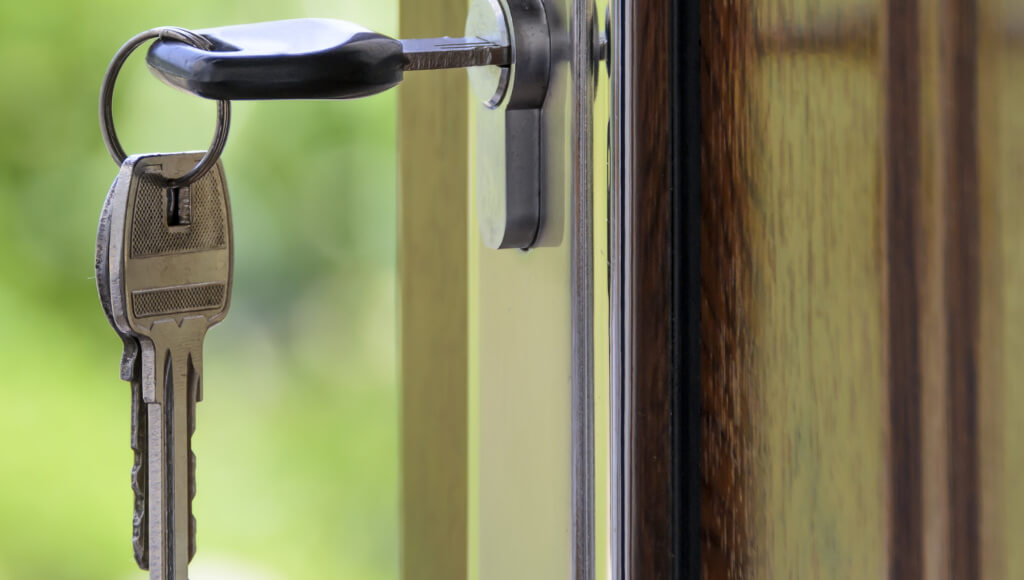 Offen Türen laden zum Einbruch ein - sichern Sie Ihr Zuhaus. Einbruchschutz beugt vor. Offen Tür mit Schlüssel im Schlüsseloch.